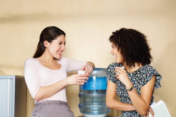 Two women speaking beside a water cooler in an office