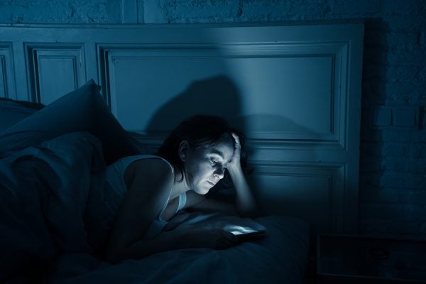A woman looking at her phone in bed