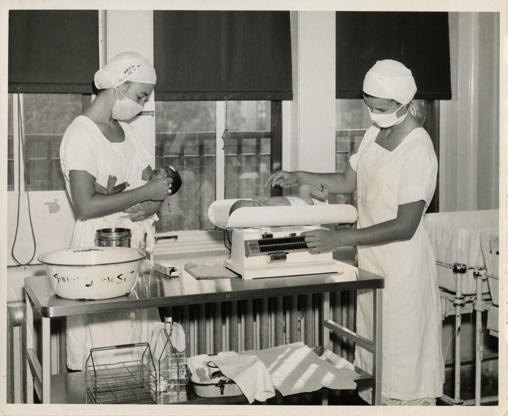 Two nurses weigh babies in the Nursery, c. 1954