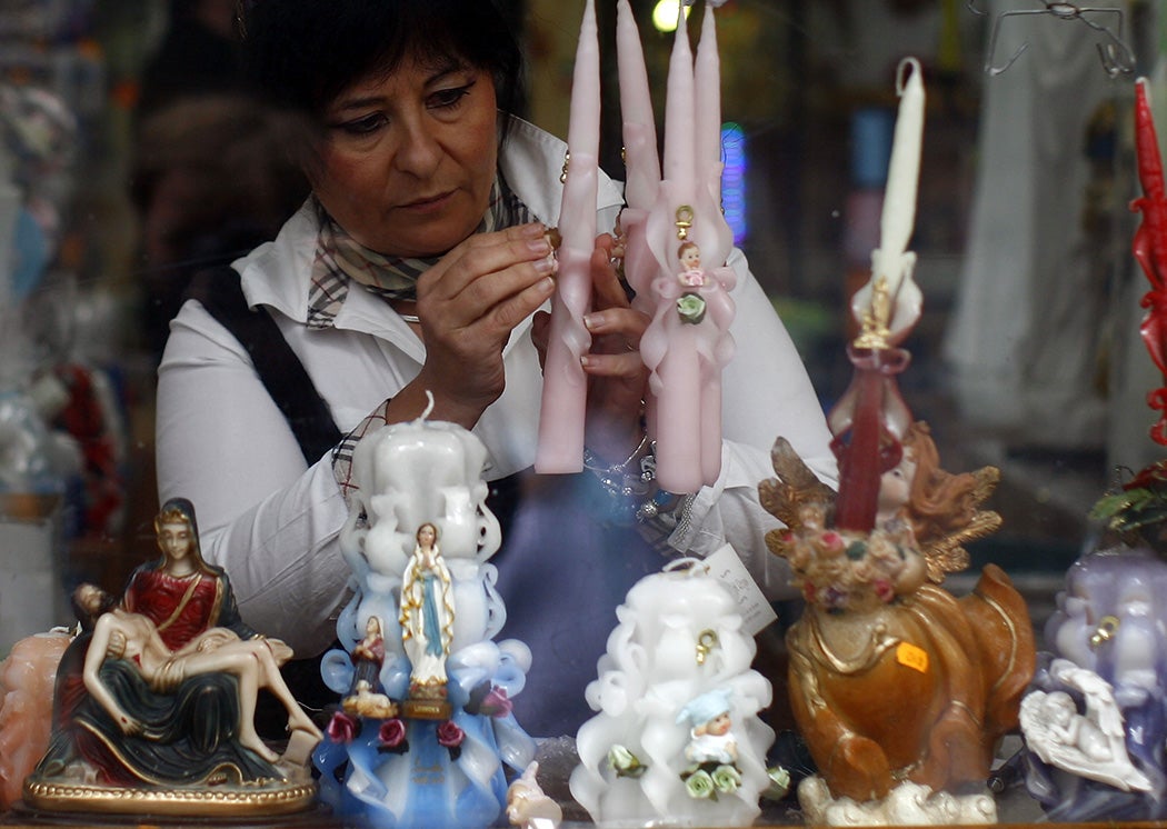 A woman arranges candles in the window of a store for holy kitsch on September 12, 2008 in Lourdes, France.