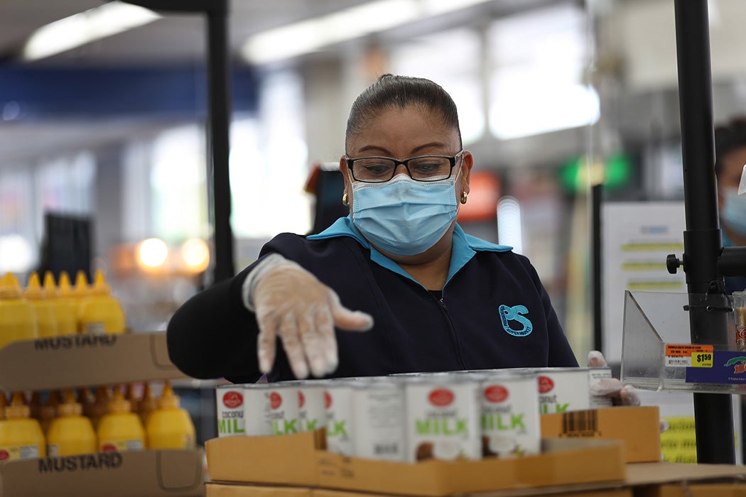 Lorena Martinez wears a mask and gloves as she works as a cashier at the Presidente Supermarket on April 13, 2020 in Miami, Florida.