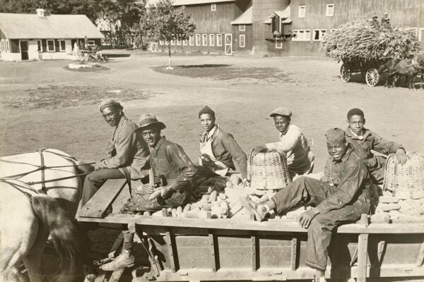 Six young men riding on a horse-drawn wagon filled with corn at the Manual Training and Industrial School for Colored Youth in Bordentown, NJ, 1935