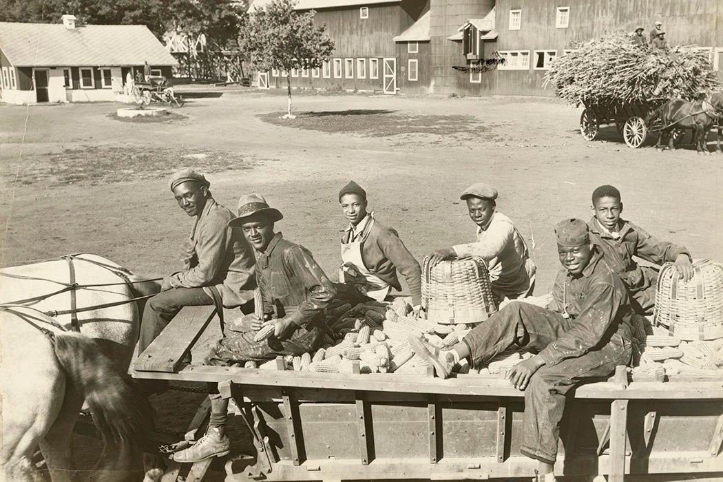 Six young men riding on a horse-drawn wagon filled with corn at the Manual Training and Industrial School for Colored Youth in Bordentown, NJ, 1935
