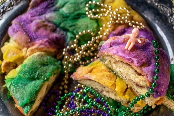 king cake with baby surrounded by mardi gras beads