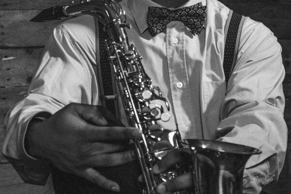 African american jazz musician with saxophone in front of old wooden wall.