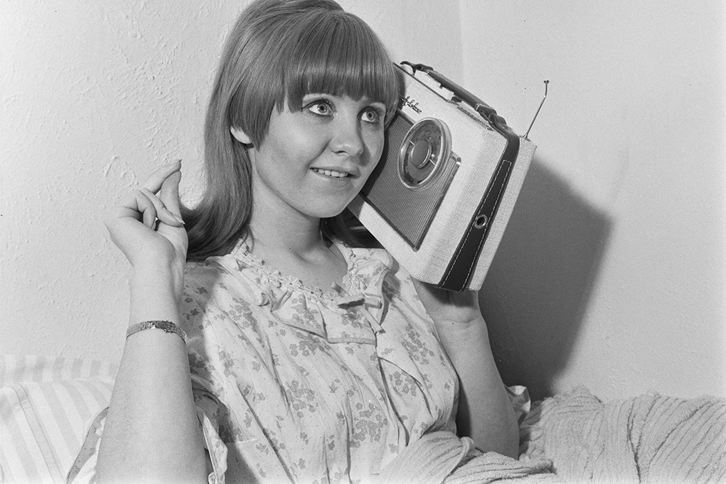 Scottish singer and actress Lulu listens to a small portable Rhapsody DeLuxe radio