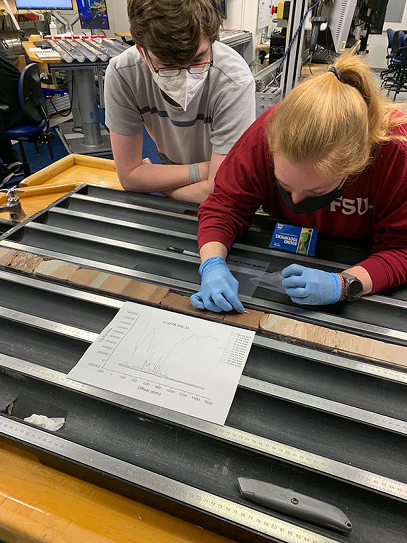 Researchers on board a research vessel in 2022 in the western South Atlantic take samples along the length of sediment cores in search of marine fossils. The sediment being examined dates from the Paleocene-Eocene Thermal Maximum — a warming event from 56 million years ago.