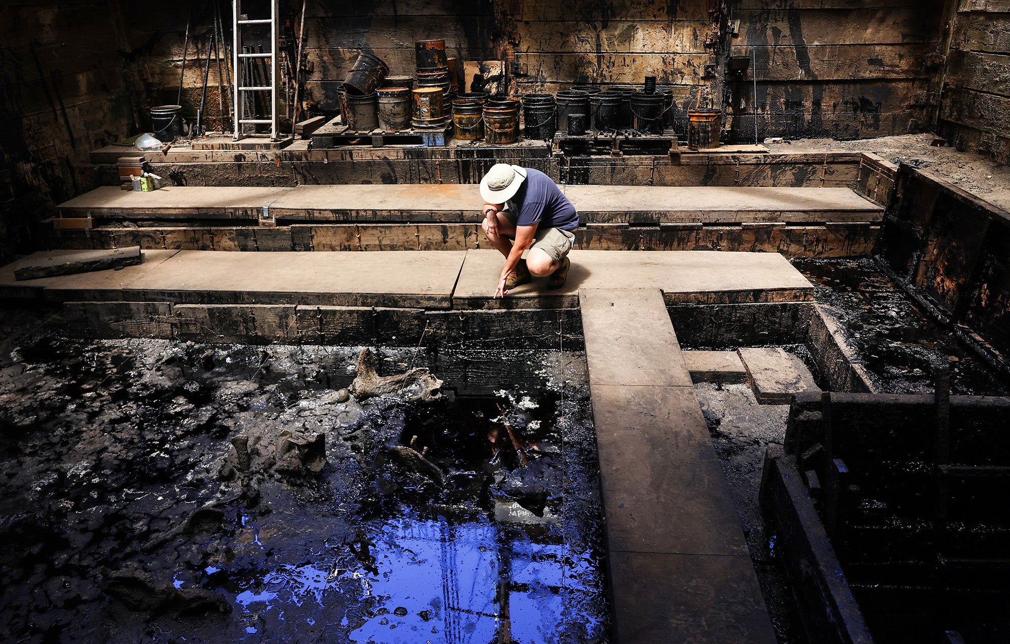 Senior fossil preparator Karin Rice kneels near mammal bones protruding from pit 91 during a media tour at the La Brea Tar Pits on August 17, 2023 in Los Angeles, California.