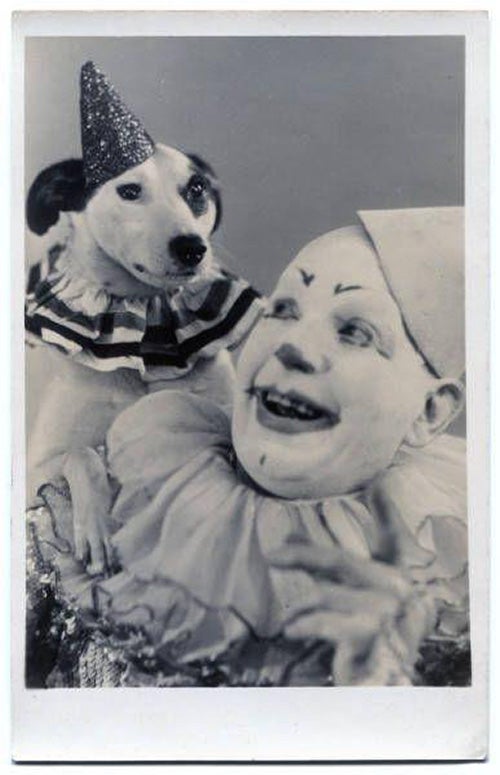 Publicity postcard photographic print of Joe Craston in a clown costume with a dog in costume on his shoulder.